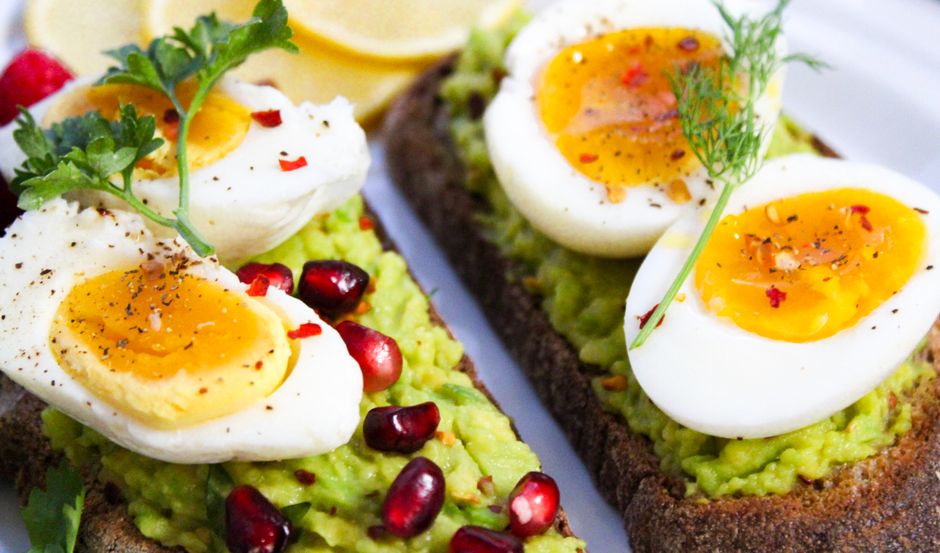 Avocado toast topped with a poached egg, chili flakes, and seeds
