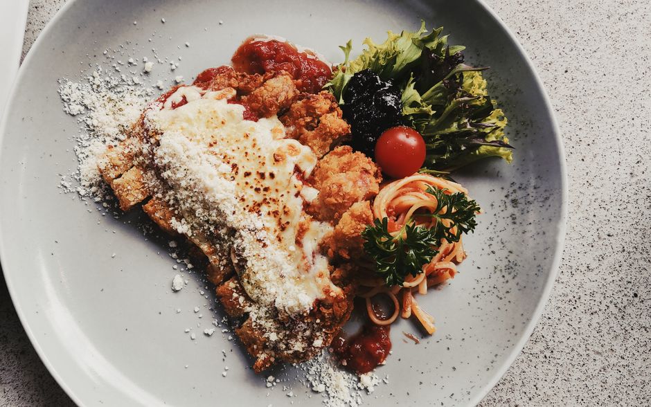 Crispy baked chicken Parmesan with melted cheese over spaghetti