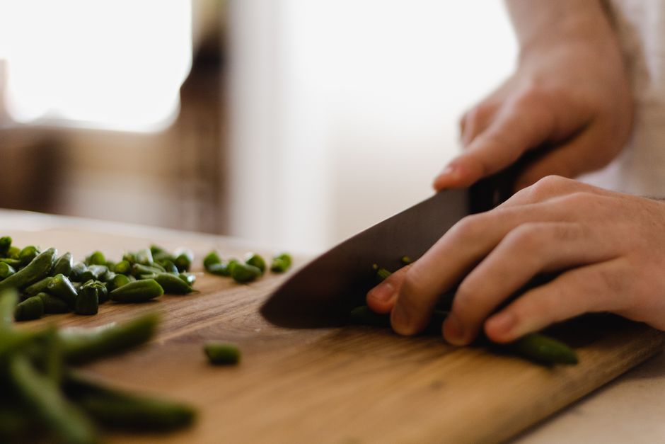 A chef's knife slicing fresh vegetables on a cutting board