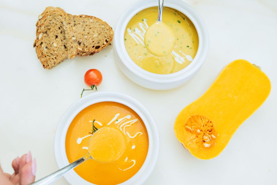 Delicious pumpkin soup served with sliced bread and cherry tomato. Perfect for a cozy meal.