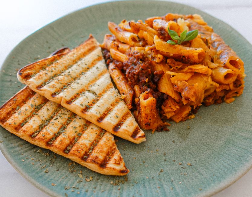 Cheesy baked ziti being scooped from a baking dish