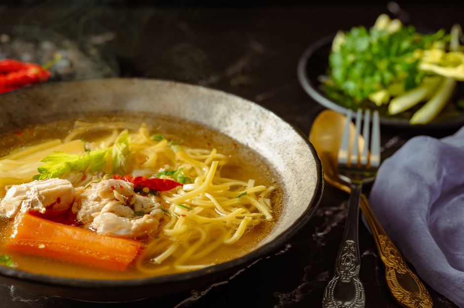 A bowl of classic chicken noodle soup with carrots, noodles, and herbs