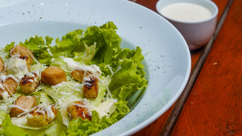 Fresh Caesar salad with crisp lettuce, croutons, and cheese in a white bowl.