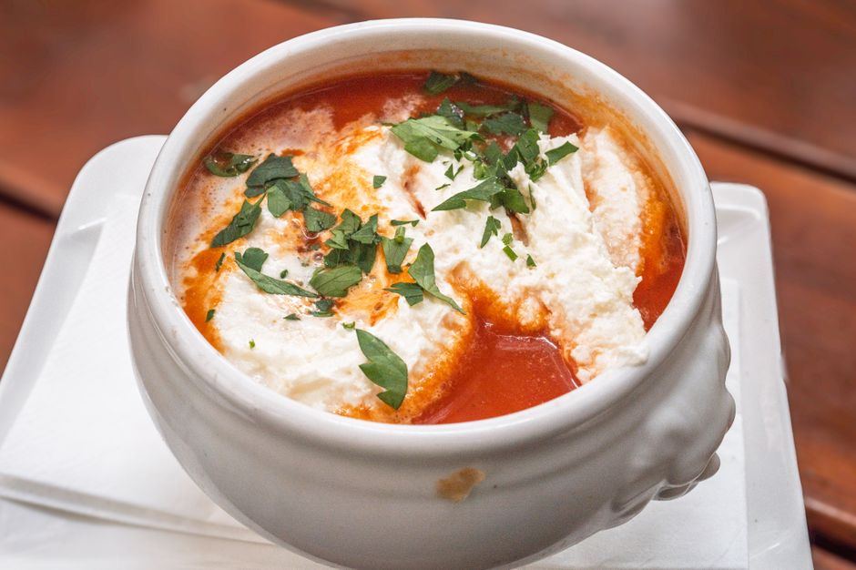 A bowl of creamy tomato soup with grilled cheese on the side