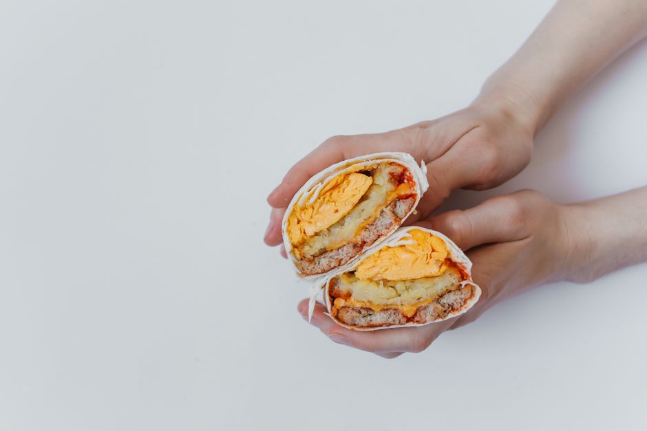 Make-ahead breakfast burritos wrapped in foil, one cut open