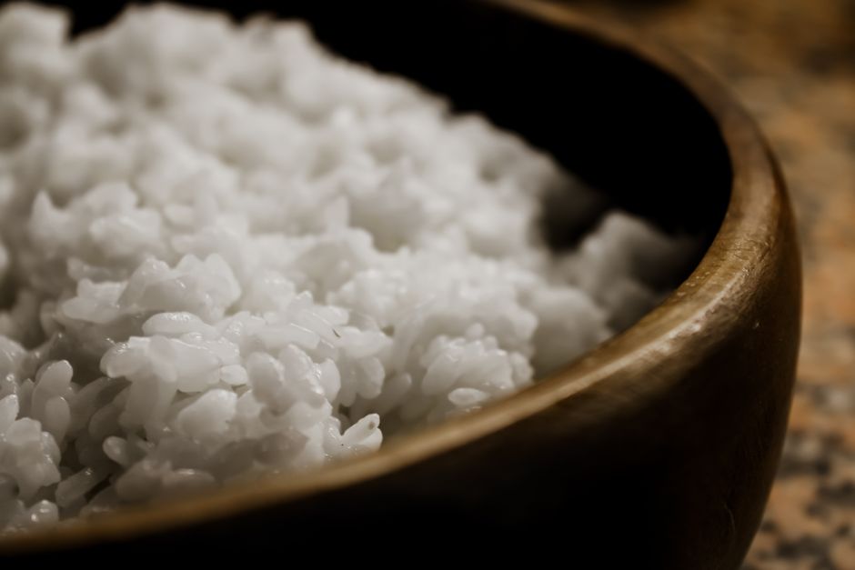 Fluffy cooked white rice being fluffed with a fork in a pot