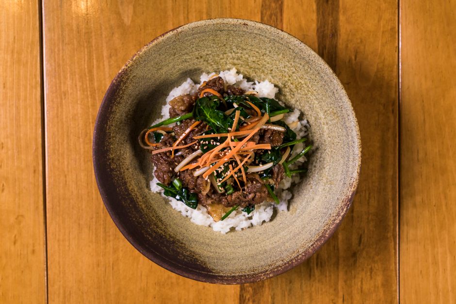Top view of a delicious Korean beef dish served in a ceramic bowl on a wooden table.