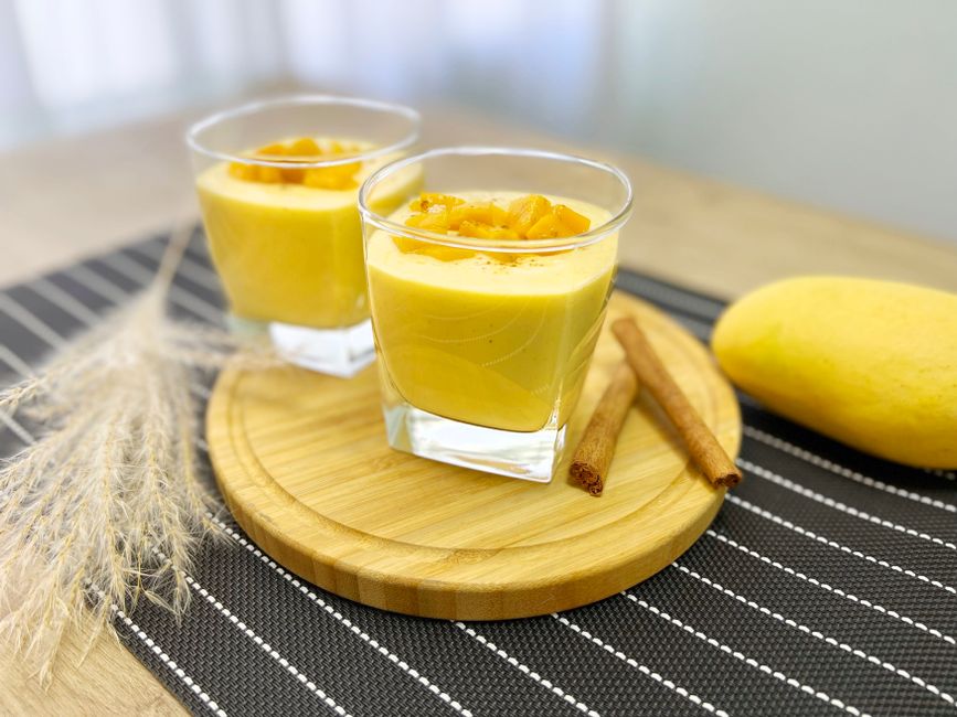 A creamy mango lassi in a glass garnished with mango