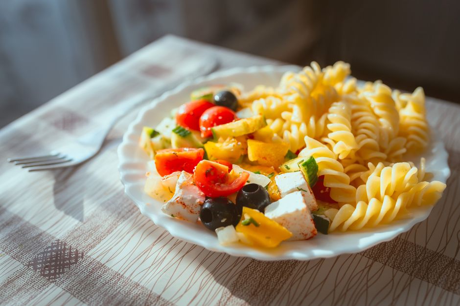 A bowl of Mediterranean pasta salad with feta, olives, and herbs
