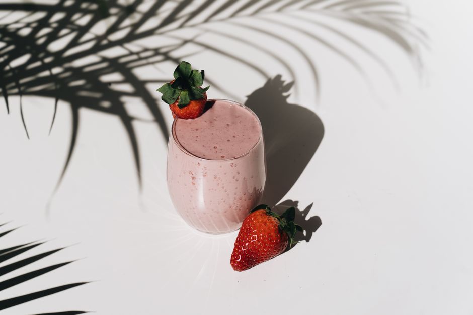 A thick strawberry banana smoothie in a glass with a straw