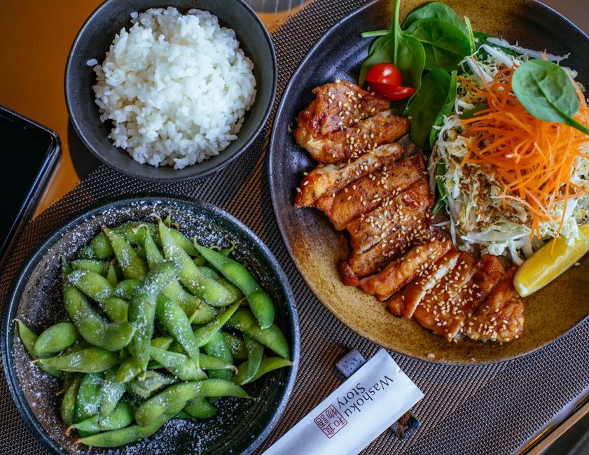A teriyaki salmon rice bowl with edamame, carrots, and sesame