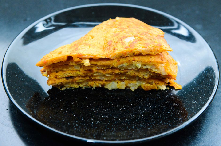 Delicious layered omelette served on a black plate, perfect for brunch or dinner.
