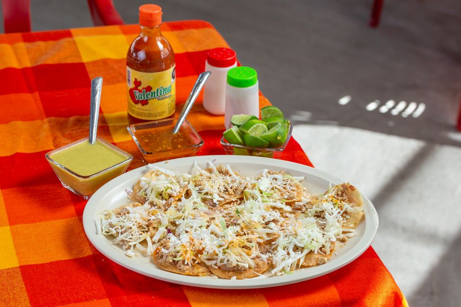 Crispy birria tacos stacked with melted cheese next to a bowl of red consommé for dipping