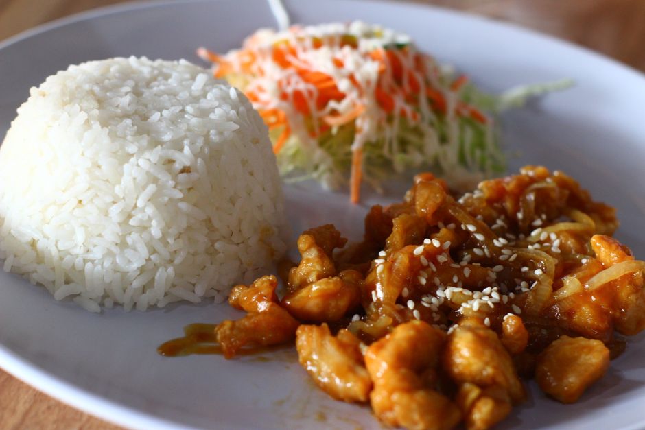 Plate of Filipino chicken bistek with caramelized onions over rice