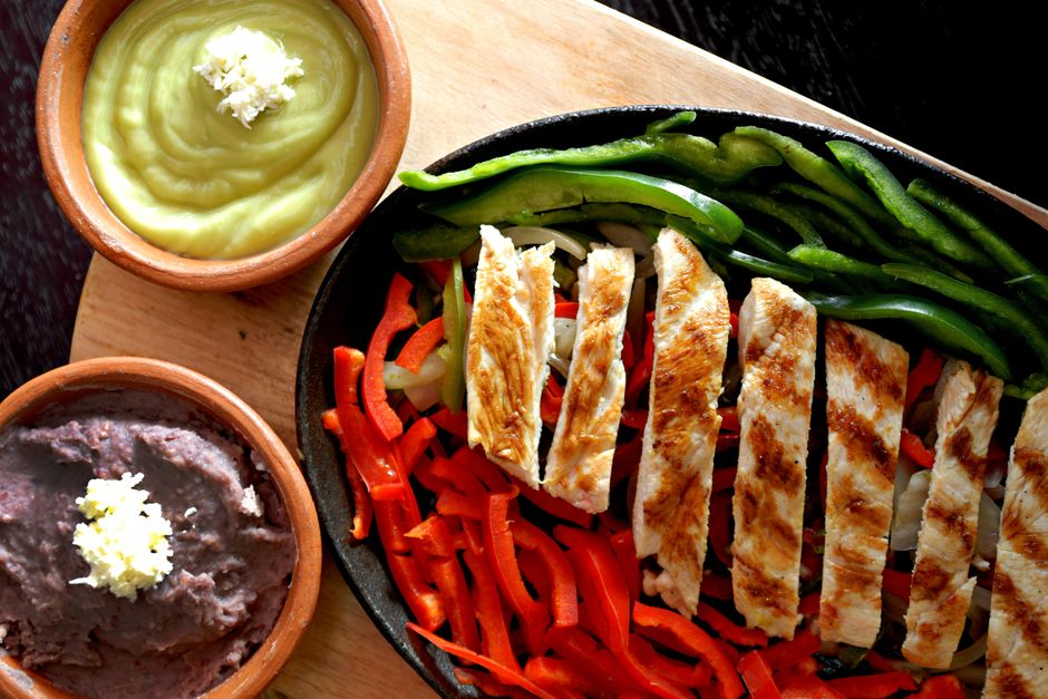 Sheet pan of chicken fajita strips with colorful bell peppers and onions