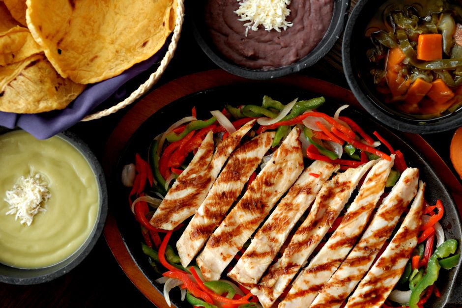 Sheet pan fajitas served with warm tortillas, lime wedges, and toppings