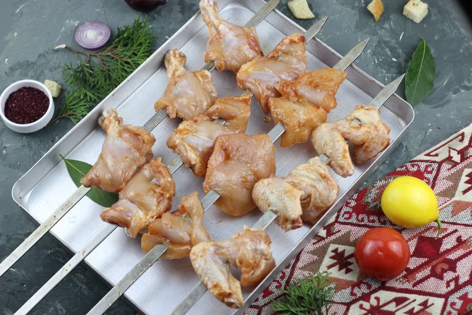 Chicken strips marinating in a bowl with warm spices and garlic