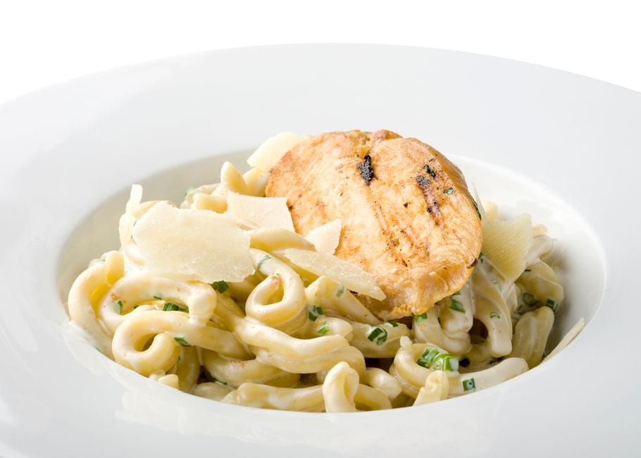 Bowl of creamy chicken pasta topped with grated parmesan