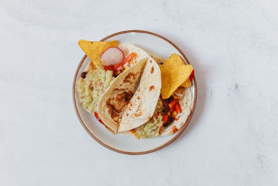 Sweet potato and black bean tacos topped with lime, cilantro, and avocado