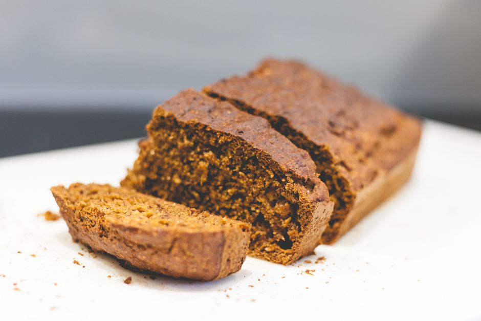 Sliced loaf of banana bread on a wooden cutting board with ripe bananas nearby