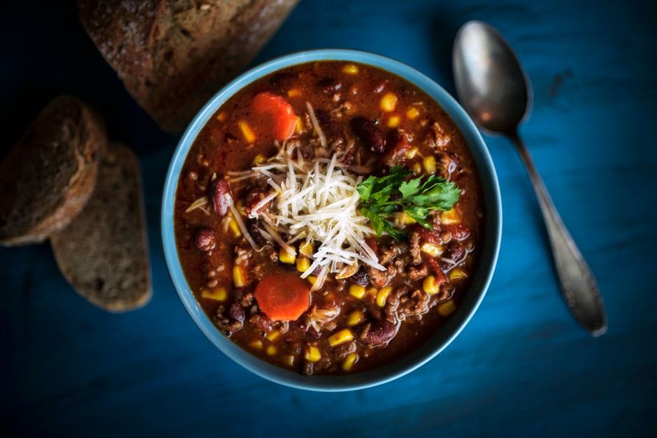 Bowl of turkey chili topped with shredded cheese, avocado, and cilantro