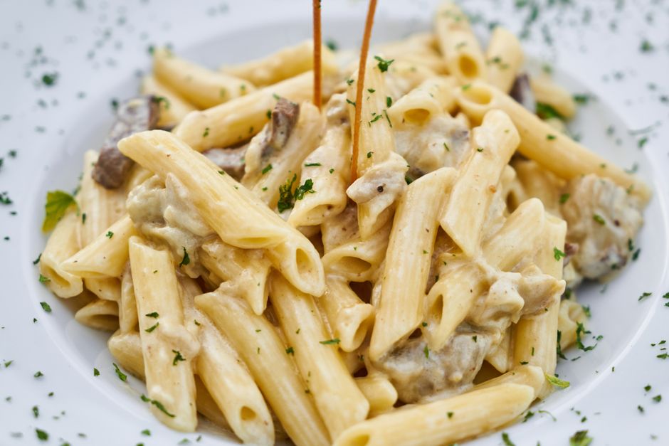 Blended cottage cheese sauce being poured over pasta in a pot