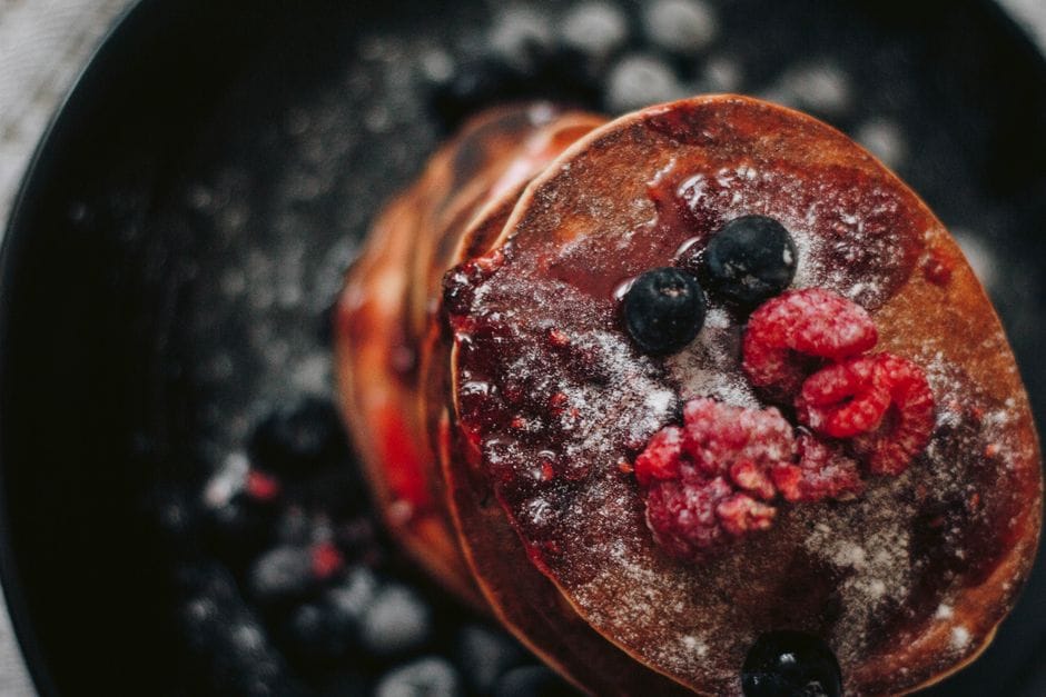 A mouth-watering stack of pancakes topped with fresh berries and powdered sugar.