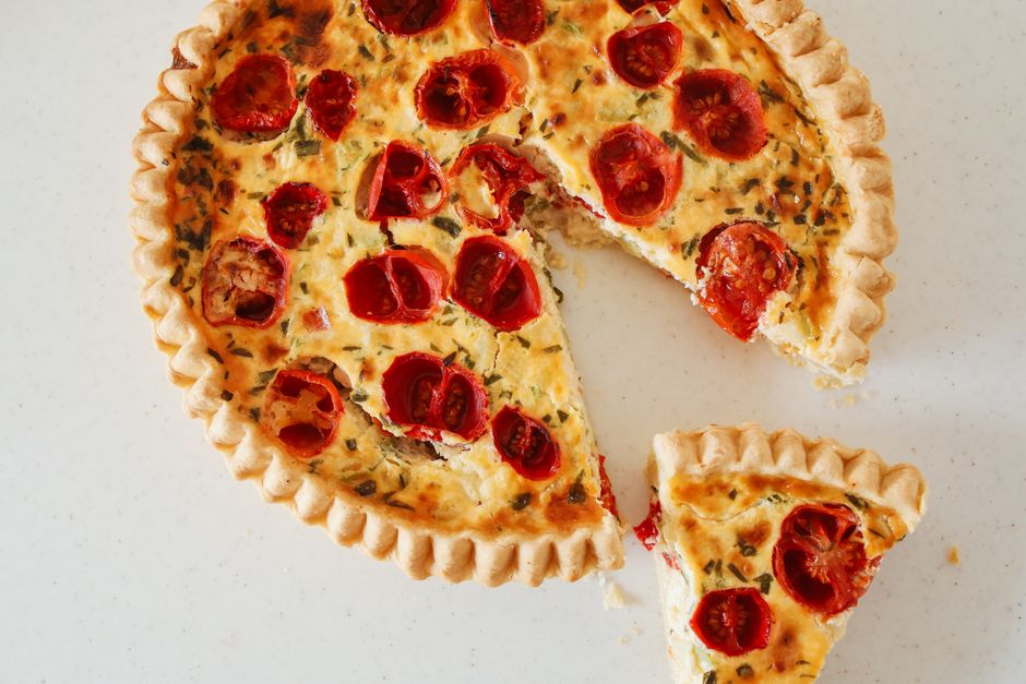 Overhead view of a whole crustless quiche in a baking dish, sliced into wedges